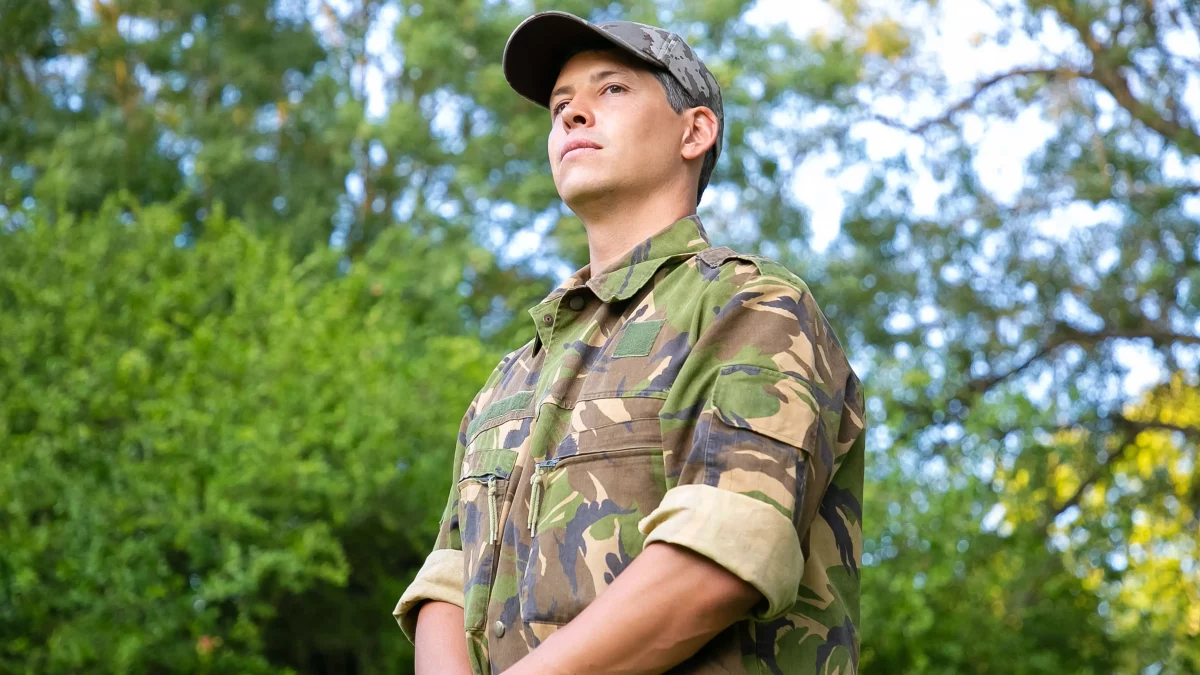 Militar de uniforme camuflado em área arborizada, representando o tema de descontos na pensão militar e a importância de avaliar cobranças legais ou indevidas.