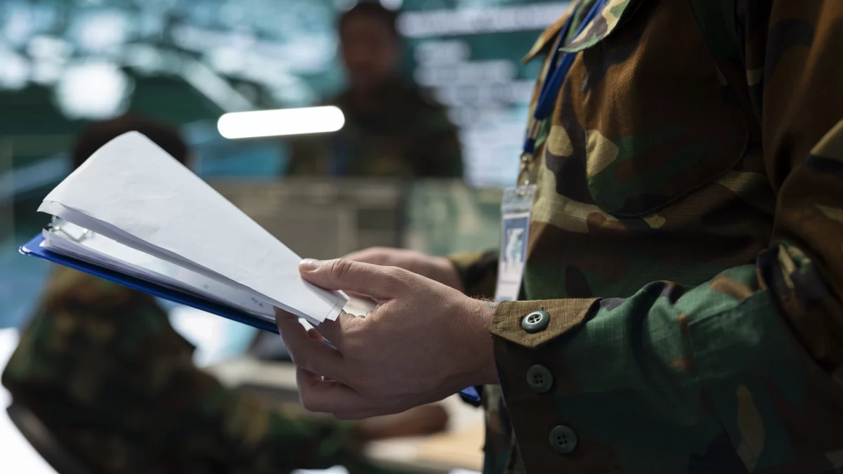 um homem em traje militar analisa documentos.