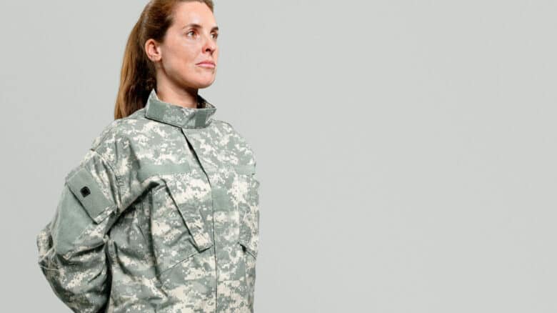 Imagem de uma mulher com as mão para trás vestida de militar para simbolizar o auxílio natalidade