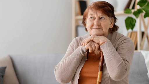 Imagem de uma senhora apoiada em uma bengala sorrindo para simbolizar plano de saúde vitalício para aposentados
