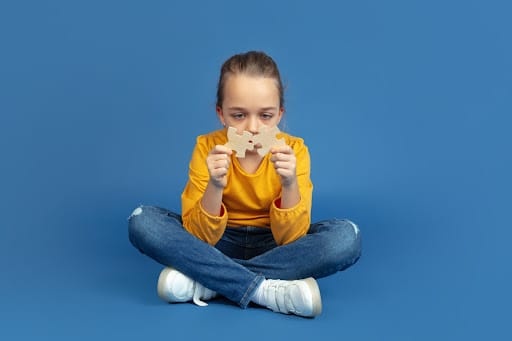 Imagem de uma menina com autismo com duas peças e quebra cabeça nas mãos para simbolizar plano de saude autismo