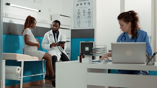 Imagem de uma sala de médico, com uma enfermeira, um médico e uma paciente grávida para simbolizar o plano de saúde cobre parto de cesárea