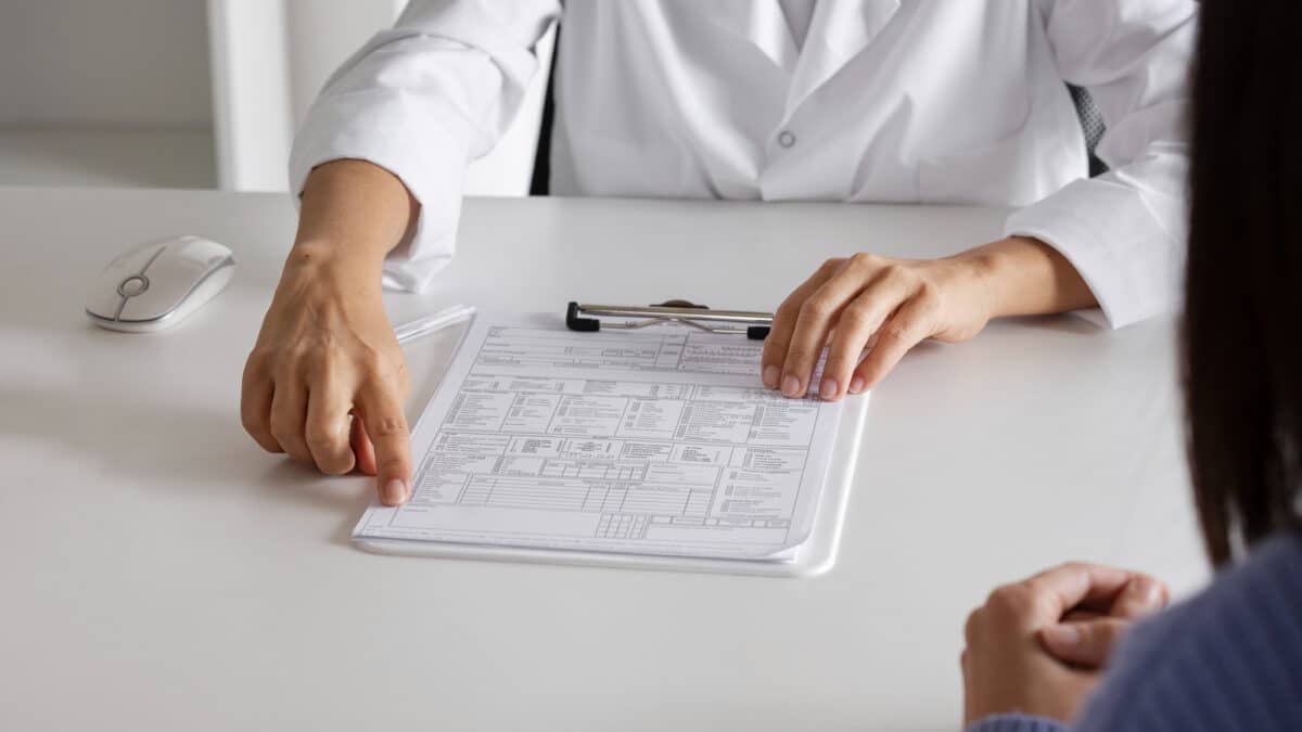 Imagem de mãos de uma médica mostrando um papel para uma paciente para simbolizar o plano de saúde pode negar portabilidade