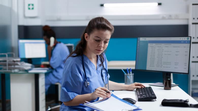 Imagem de uma enfermeira olhando e anotando algo em uma folha para simbolizar o hospital pode cobrar procedimento não autorizado pelo plano de saúde