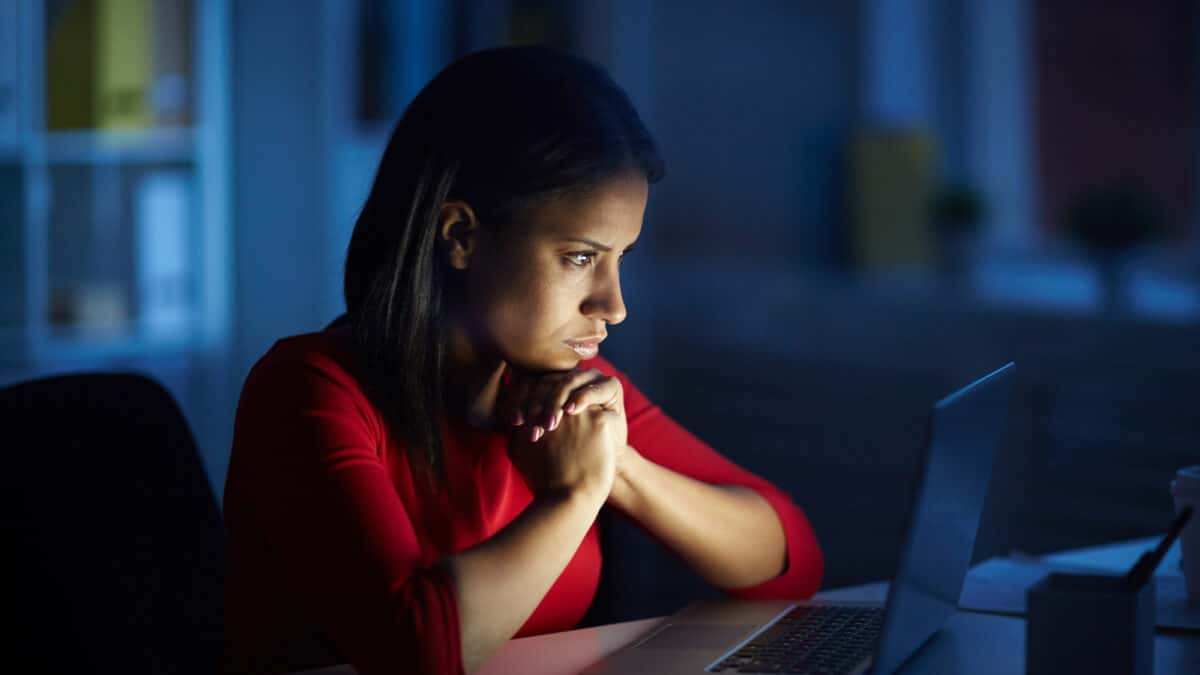 Imagem de uma mulher com as mãos apoiadas no queixo e na frente do computador para simbolizar o benefício indeferido