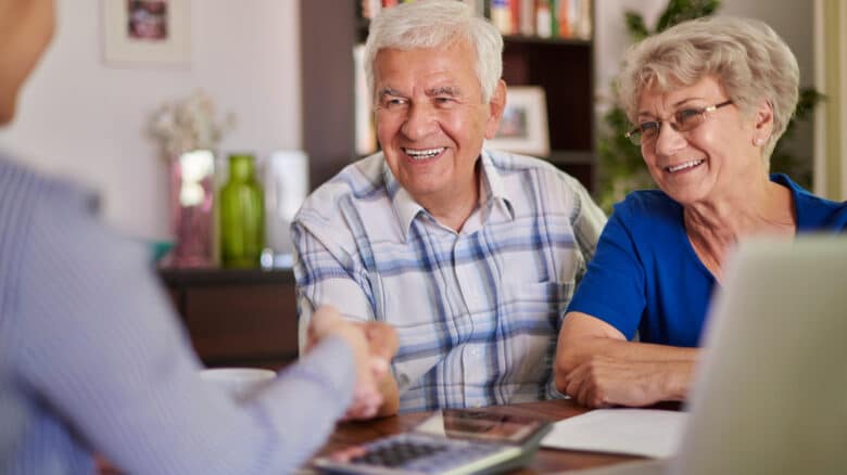 Imagem de um casal de idosos sorrindo e falando com um homem para simbolizar o Dia da Previdência Social
